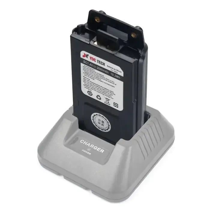 Black walkie-talkie battery charging in a gray desktop charger.