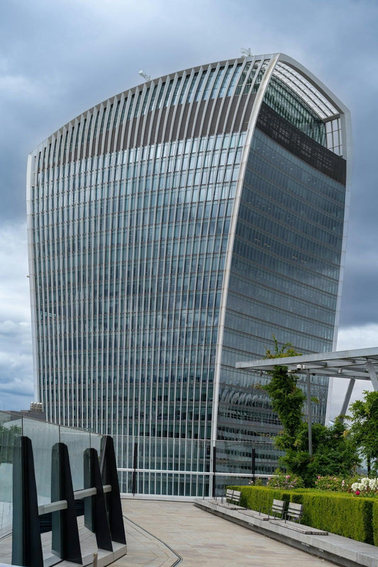 Modern skyscraper with curved glass facade against cloudy sky.