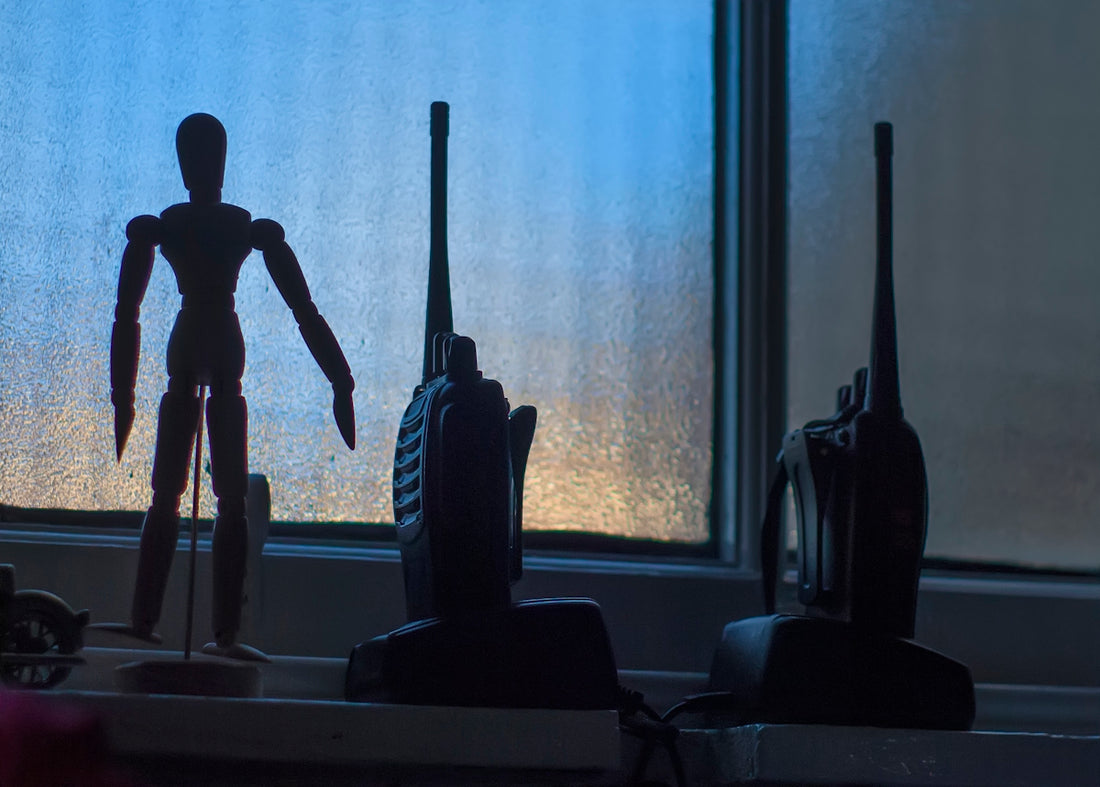 Wooden mannequin and two walkie-talkies on windowsill.