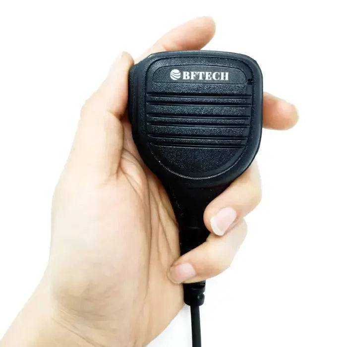 A black handheld two-way radio microphone with a coiled cord.