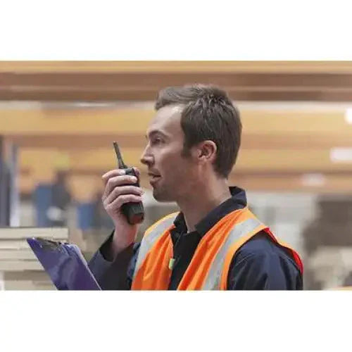Worker in a high-visibility safety vest using a handheld radio.